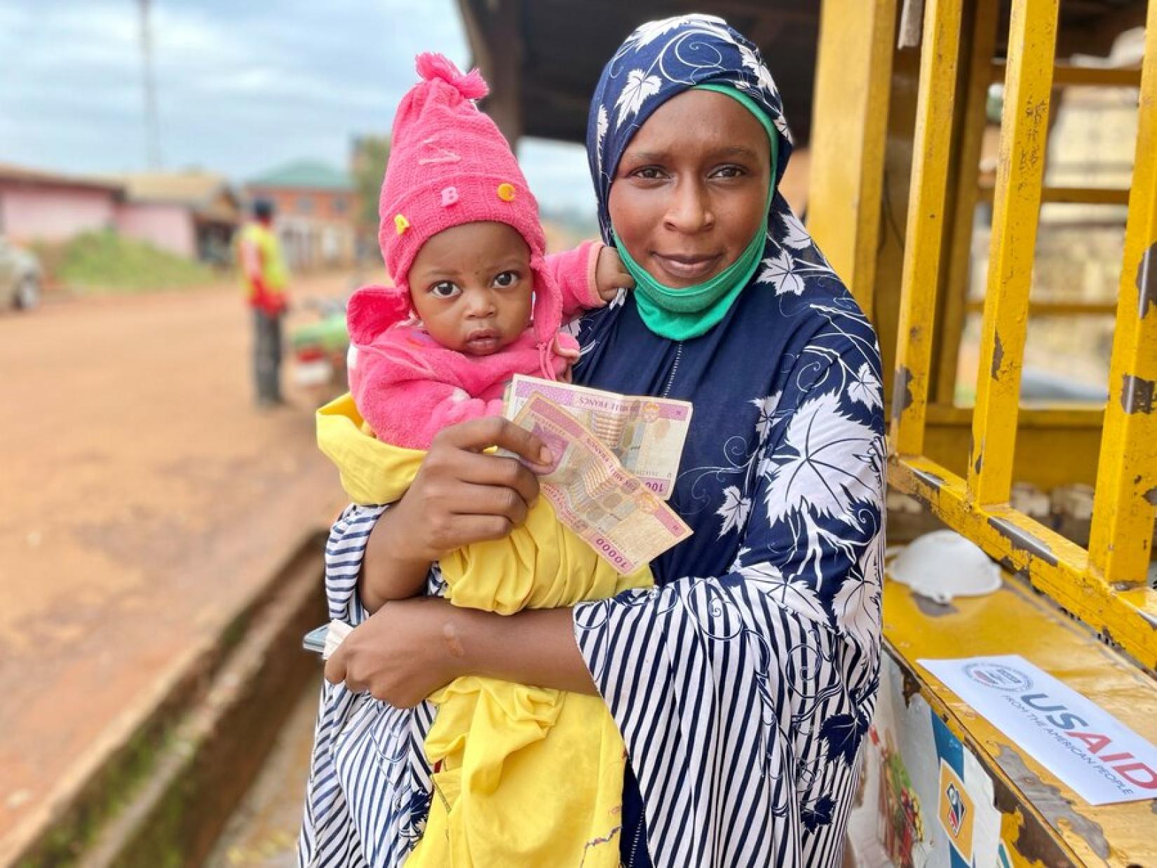 Djanabou withdraws the money she receives from WFP at a certified partner's booth