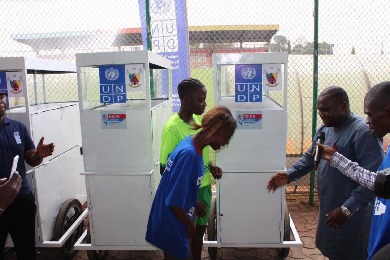 The rep. of the Ministry of Youth Affairs and Civic Education, handing over mobile kiosks to vulnerable young women
